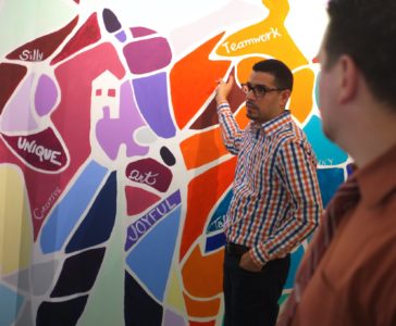 Arturo Arroyo of Svigals + Partners showing off a mural painted by their team with Fathom